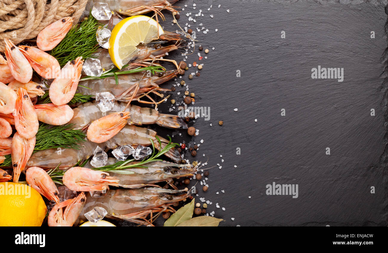Gamberetti freschi con spezie sulla pietra nera dello sfondo. Vista da sopra con lo spazio di copia Foto Stock