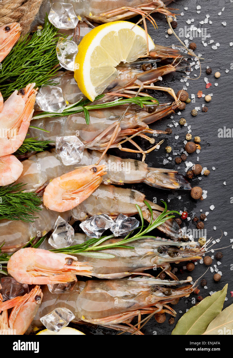 Gamberetti freschi con spezie sulla pietra nera dello sfondo. Vista superiore Foto Stock