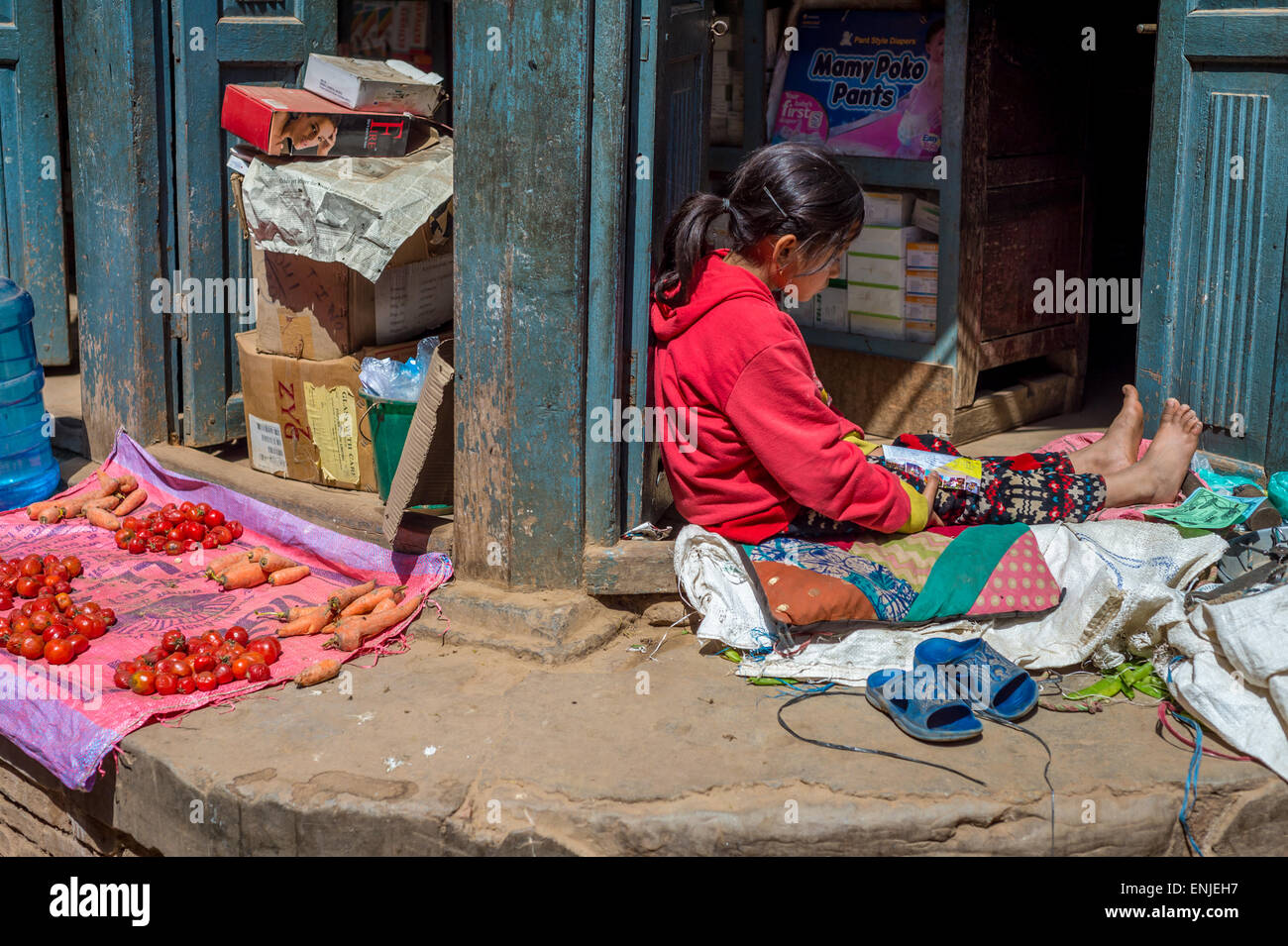 Bhaktapur, 20 marzo 2015 - una ragazza nepalese sta leggendo una rivista mentre è seduto sul pavimento Foto Stock