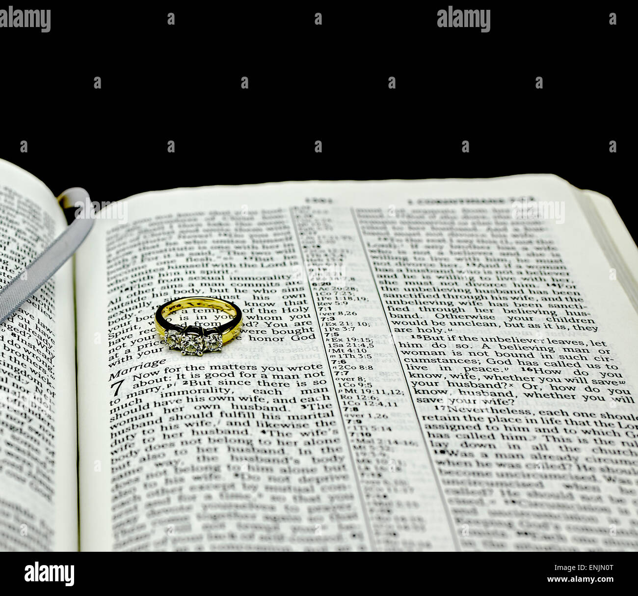 Singolo diamante anello nuziale sulla Bibbia aperta al matrimonio su sfondo nero Foto Stock
