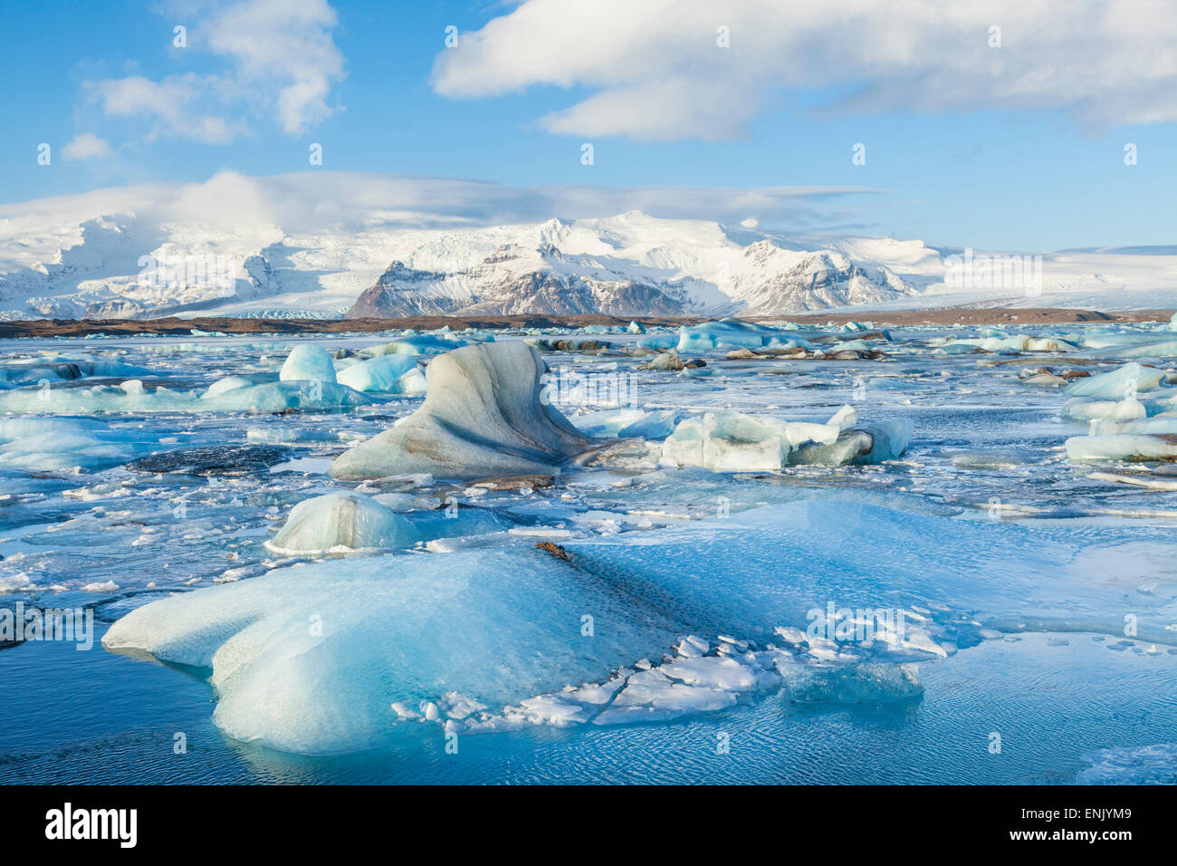 Le montagne alle spalle gli icebergs bloccato nell'acqua congelata di Jokulsarlon laguna Iceberg, Jokulsarlon, Sud Est Islanda Islanda Foto Stock