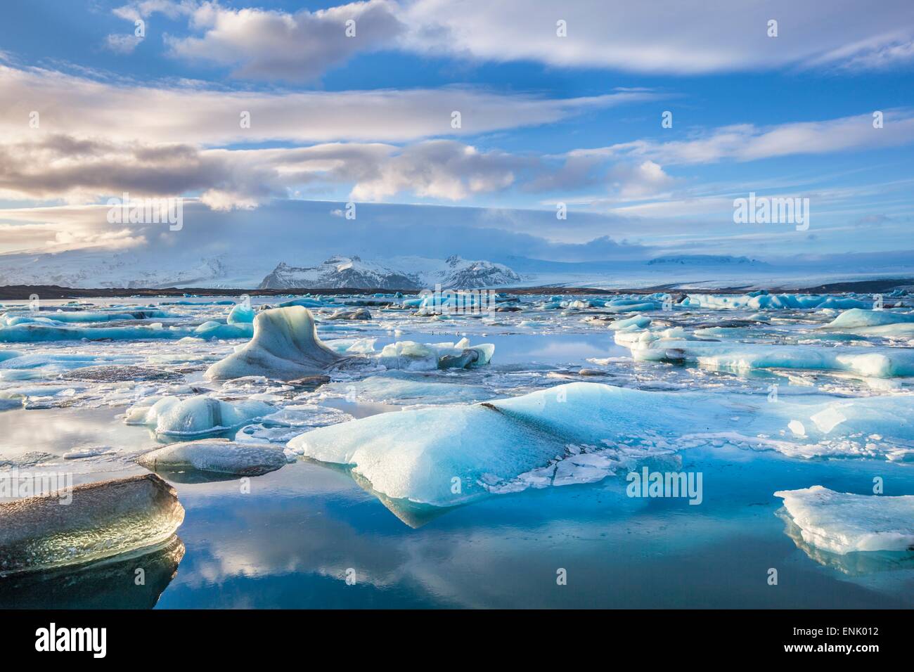 Le montagne alle spalle iceberg bloccato nell'acqua congelata di Jokulsarlon Laguna, Jokulsarlon, sud-est di Islanda Islanda Foto Stock