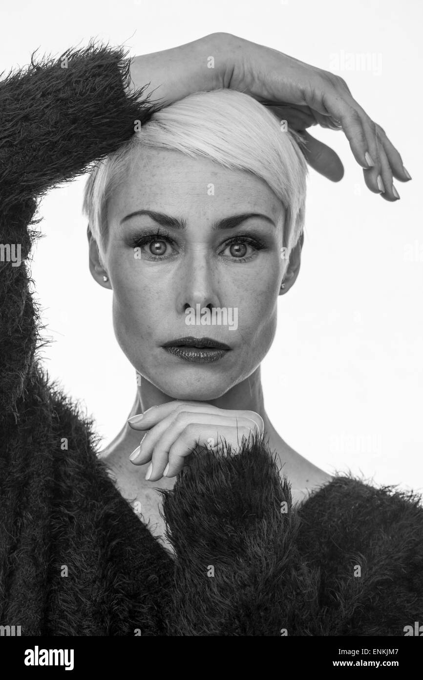 Donna matura con corti capelli biondi con la mano sulla sua testa Foto Stock