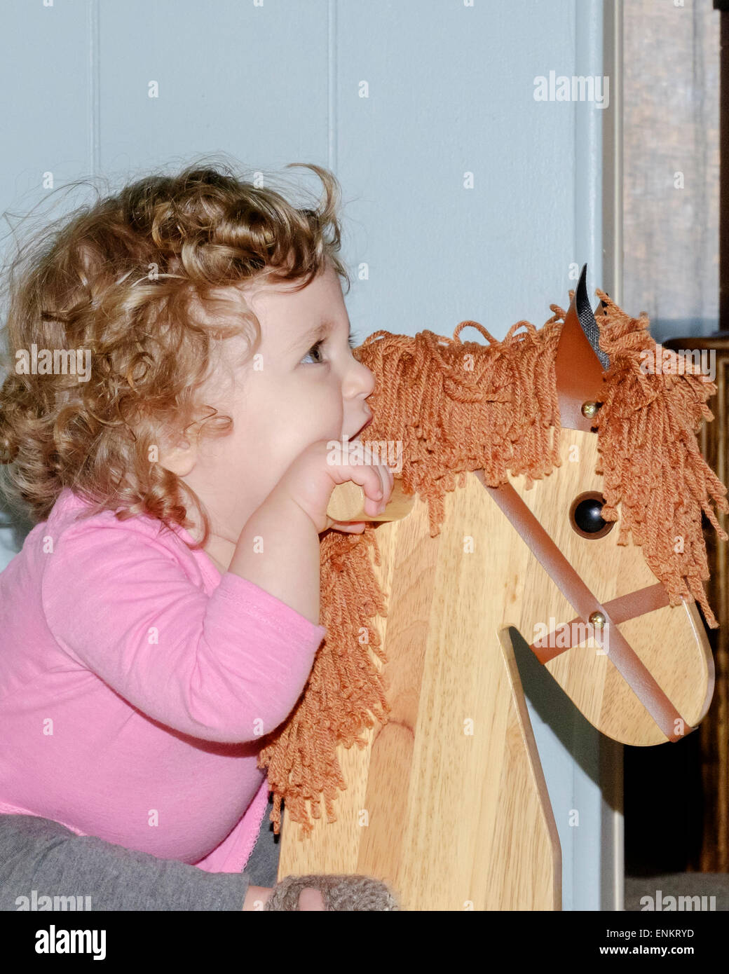 A dieci mesi di old Caucasian Baby girl cavalca il suo legno cavallo a dondolo. Foto Stock