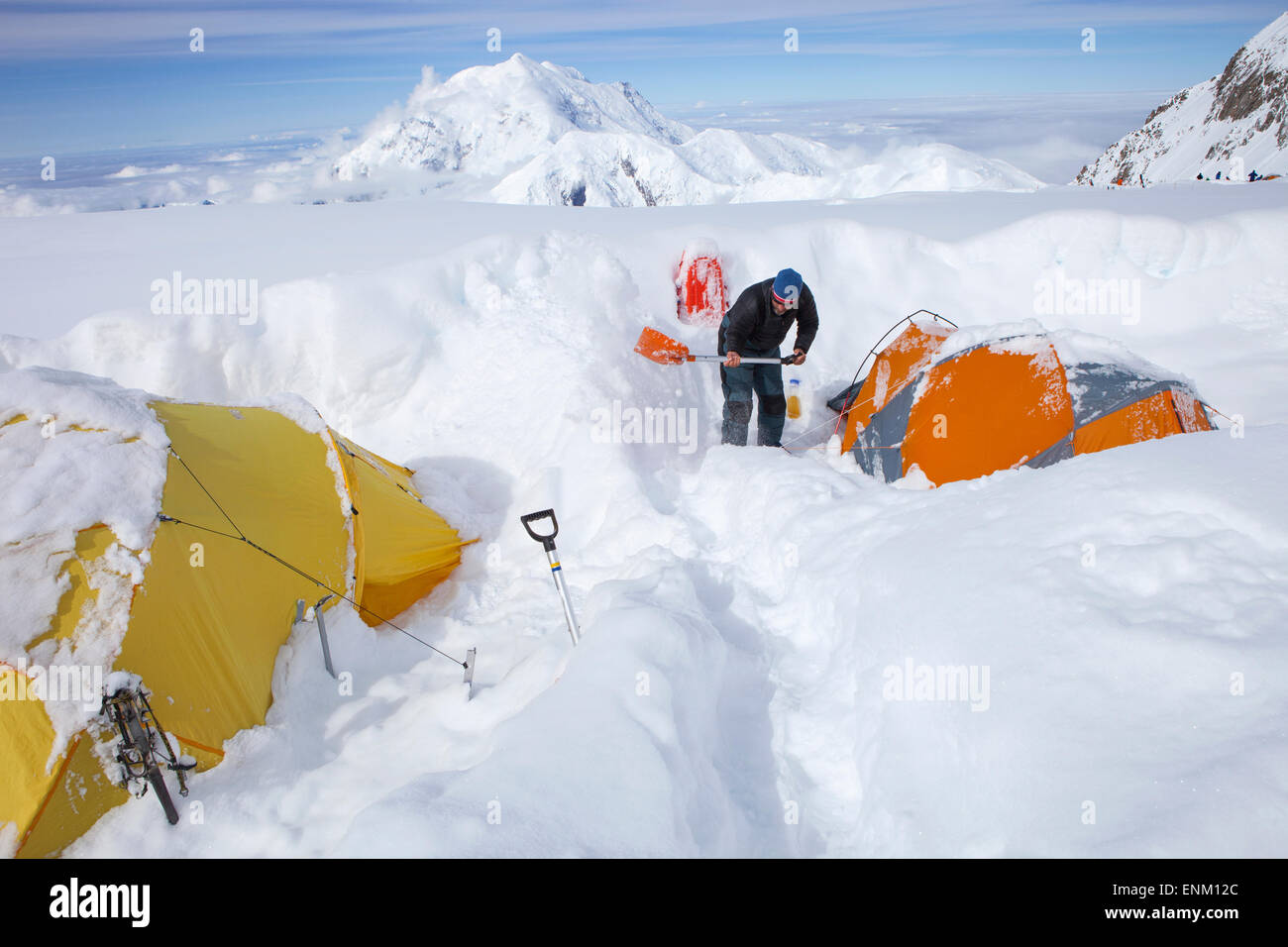 Un ranger di montagna è scavo tende dopo una tempesta di neve li ha ricoperti durante la notte in 14k camp sul Monte McKinley, Alaska. Foto Stock