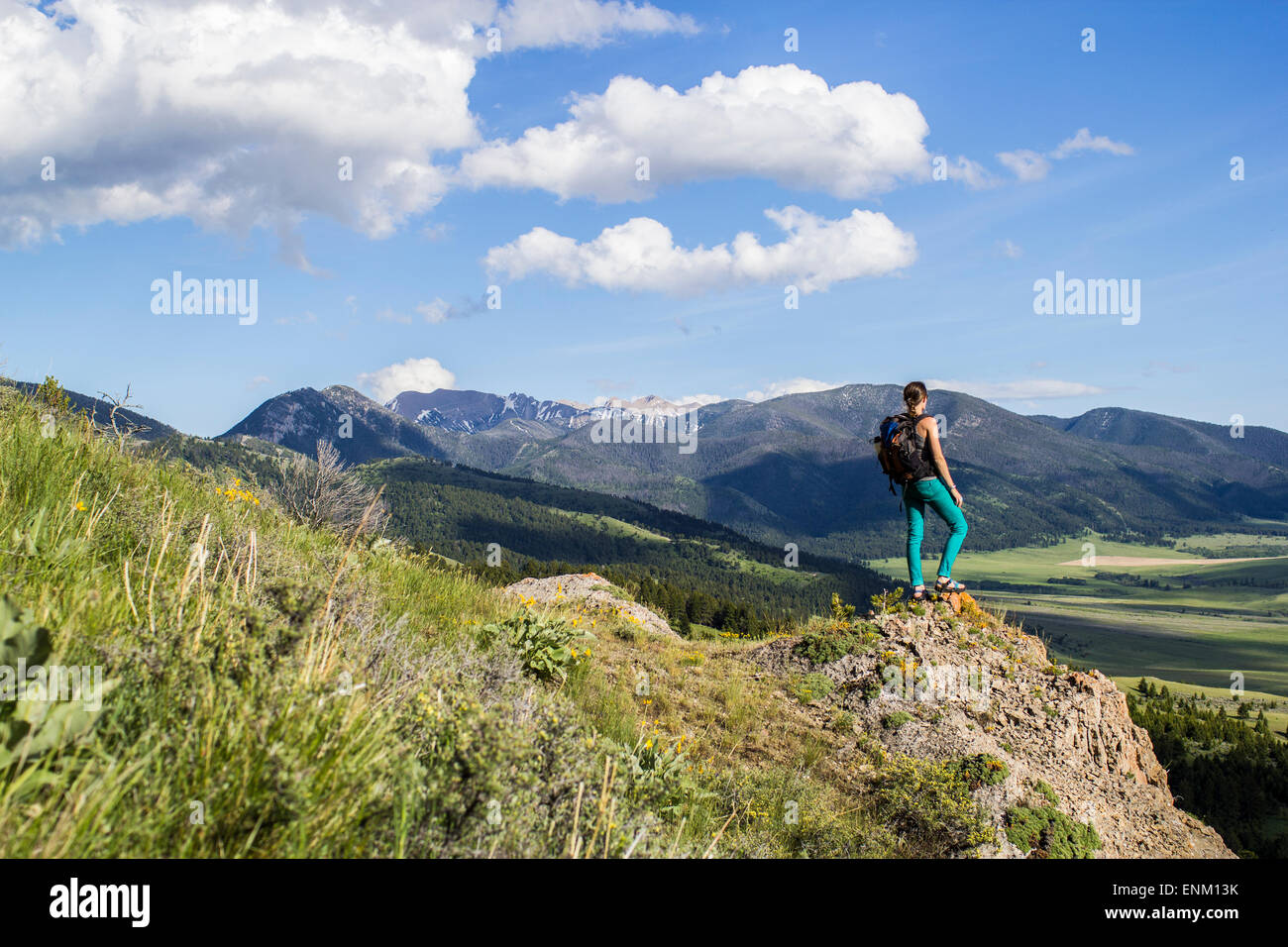 La donna si erge su una roccia che guarda fuori nelle Montagne Rocciose del Montana Foto Stock