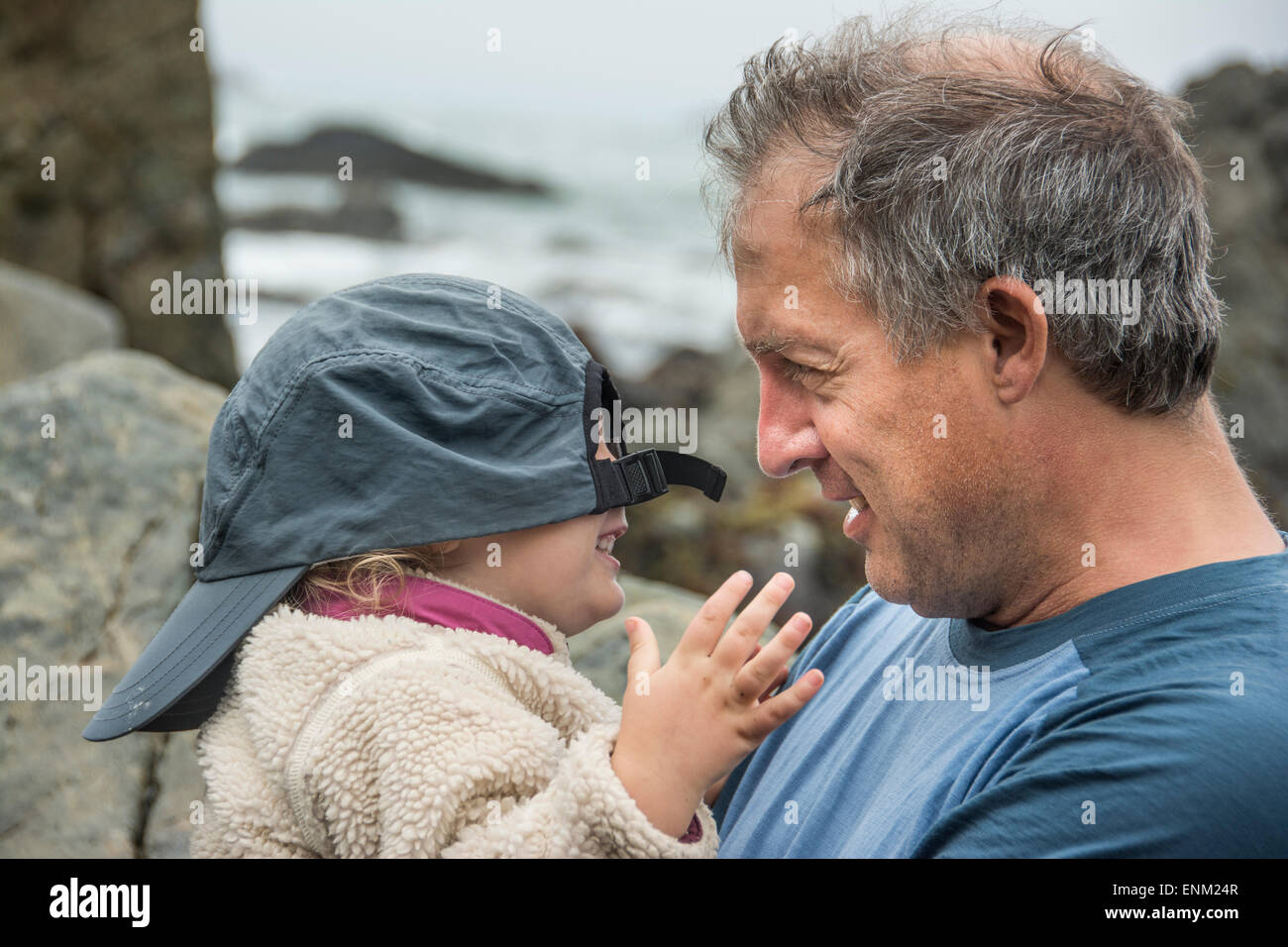 Padre gioca il peek-a-boo con toddler figlia usando il suo cappello da baseball a Patrick's Point State Park, California. Foto Stock