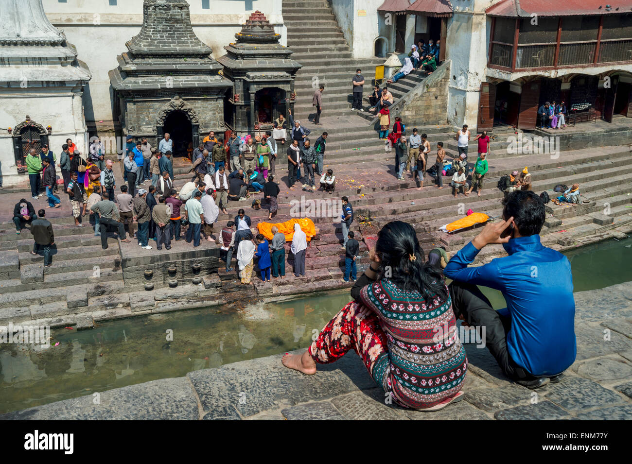 Tempio di Pashupatinath a Kathmandu. Una famiglia è in attesa per una cerimonia di cremazione accanto a un corpo morto. Foto Stock