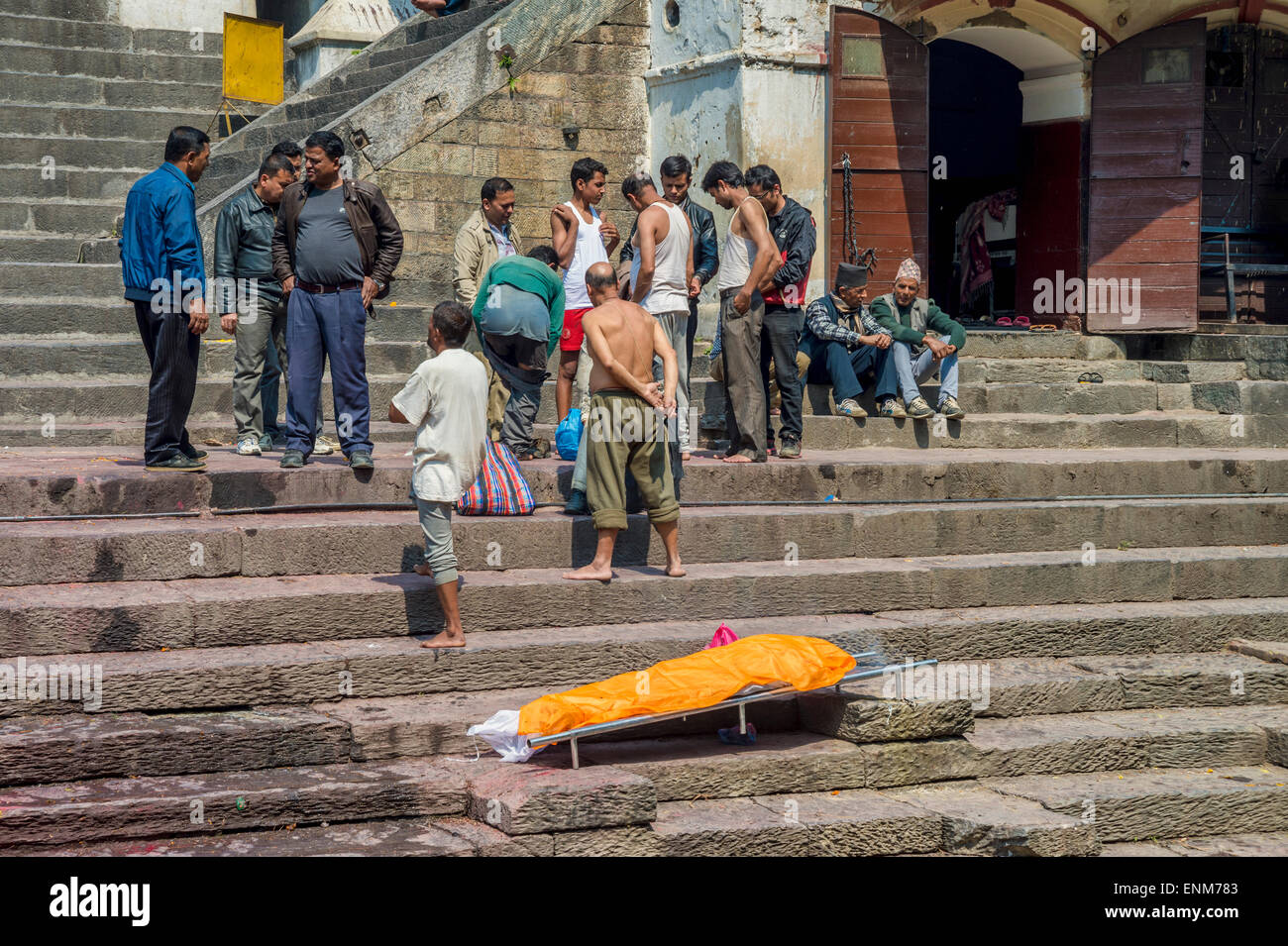 Tempio di Pashupatinath a Kathmandu. Una famiglia è in attesa per una cerimonia di cremazione accanto a un corpo morto. Foto Stock