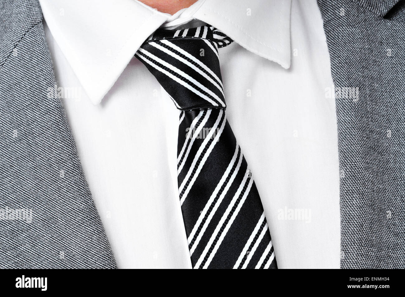 Dettaglio di un uomo che indossa una giacca grigia tuta, una camicia bianca e bianco e nero a strisce tirante Foto Stock