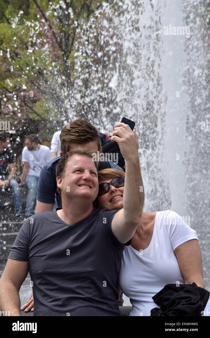Una famiglia turistica prendendo un selfie vicino alla fontana di Washington Square Park nel Greenwich Village di New York City Foto Stock
