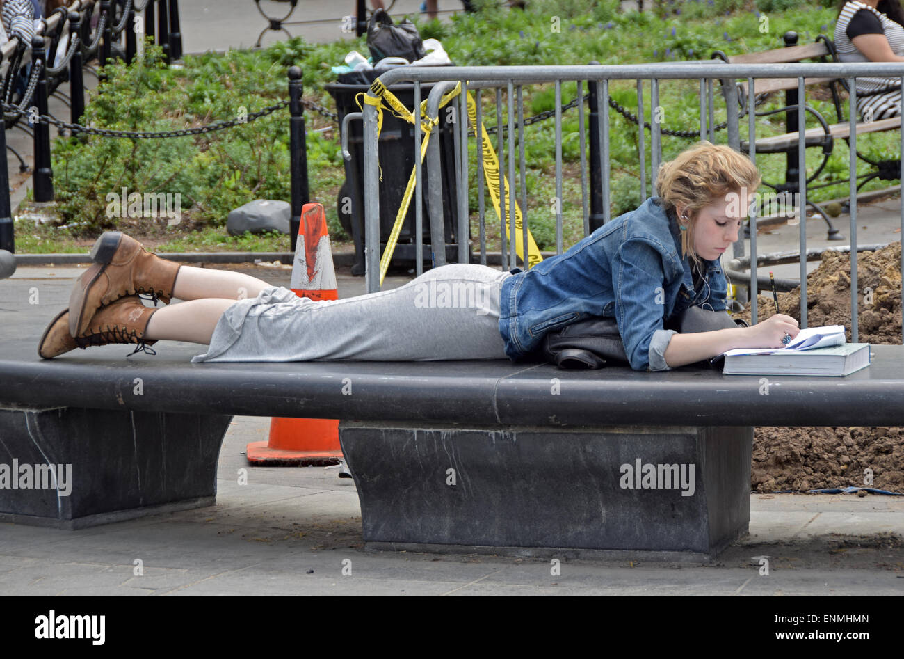 Un grazioso studente universitario che studia per gli esami all'aperto a Washington Square Park nel Greenwich Village di New York City Foto Stock