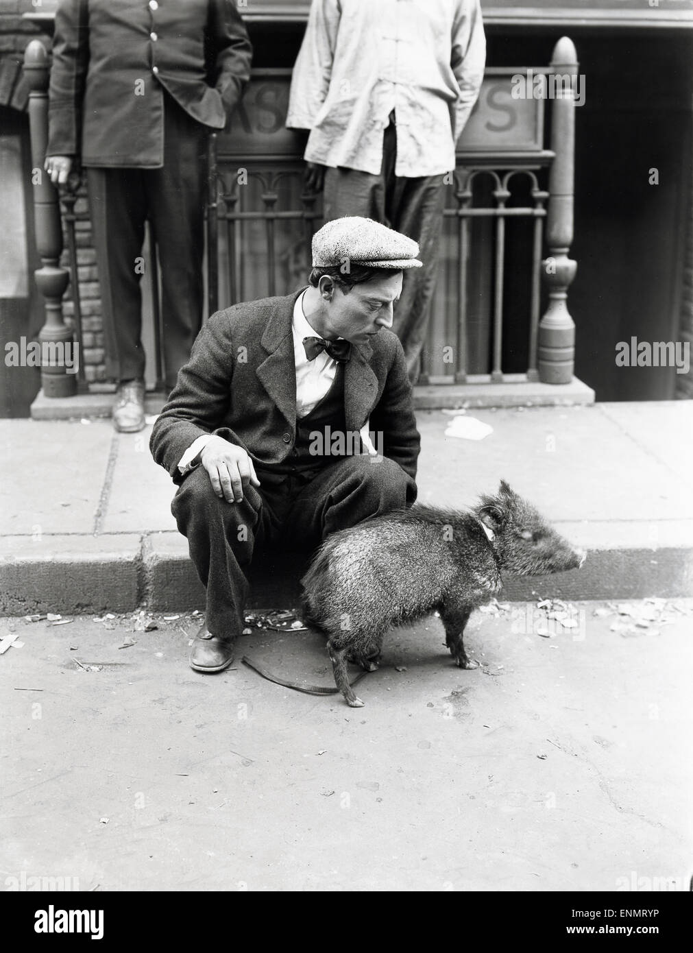 Der US-amerikanische Schauspieler Buster Keaton (1895 - 1966) spielt auf der Straße Mit einem jungen Wildschwein, ca in den 1930 Foto Stock