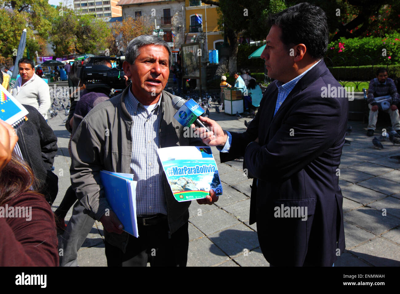 La Paz, Bolivia, 8 maggio 2015. Un uomo boliviano tiene un banner con il hashtag #MarParaBolivia (Mare per la Bolivia) mentre si parla con la stampa locale al fine di Bolivia la presentazione finale alla Corte internazionale di giustizia dell' Aia che era stato mostrato in diretta su un maxischermo nella Plaza Murillo. Le audizioni iniziali per la Bolivia il caso la bonifica di accesso all'Oceano Pacifico contro il Cile hanno avuto luogo nella CIG questa settimana le audizioni sono state a discutere il cileno obiezione che la Corte non ha competenza per giudicare il caso. Credito: James Brunker / Alamy Live News Foto Stock