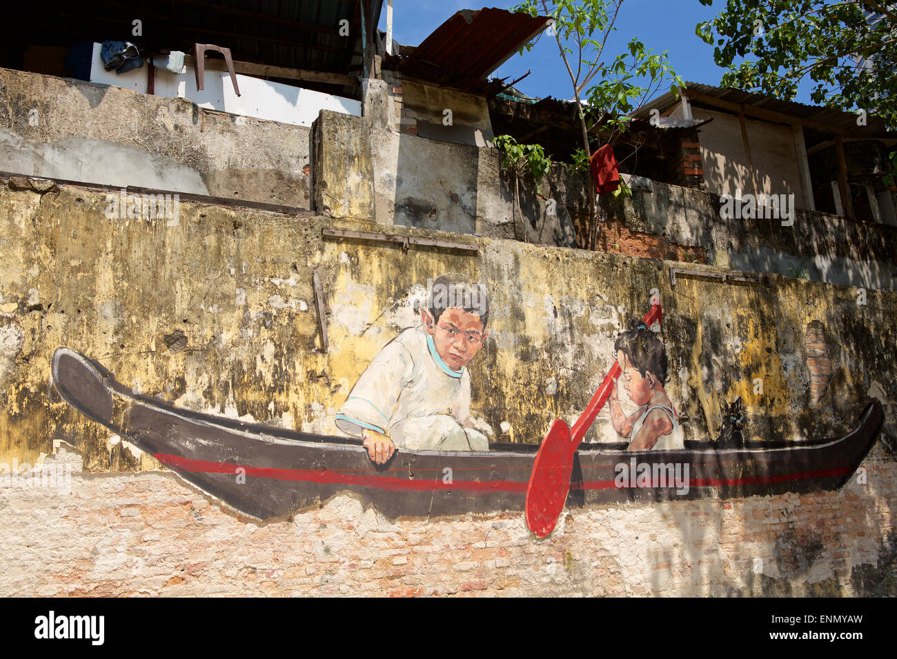 Street Art raffigurante due ragazzi in una canoa e colorati di pittura su un decadimento parete ruvida in Penang. Foto Stock