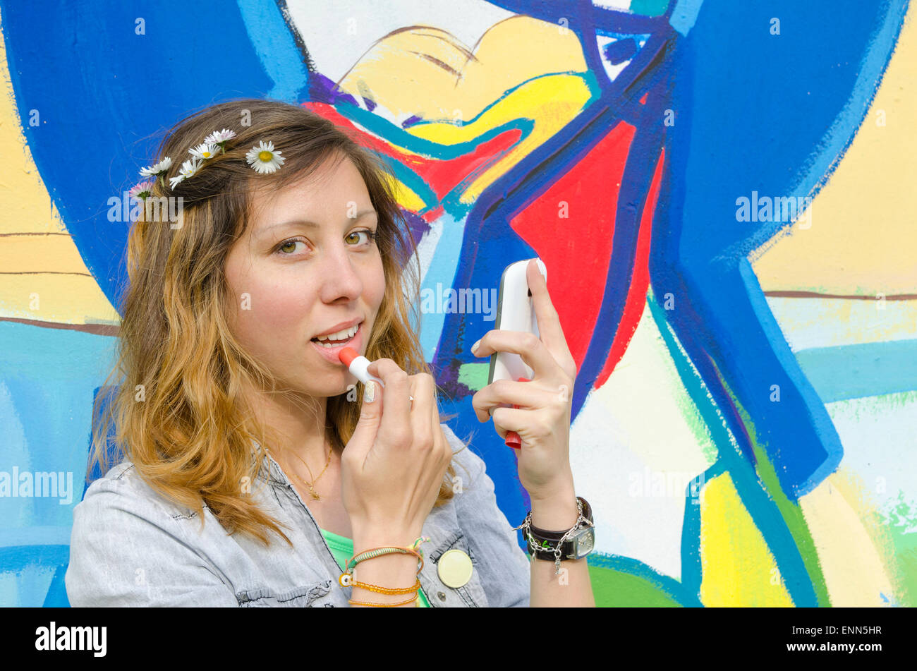 Ragazza giovane mettendo il rossetto con smart-phone come uno specchio Foto Stock