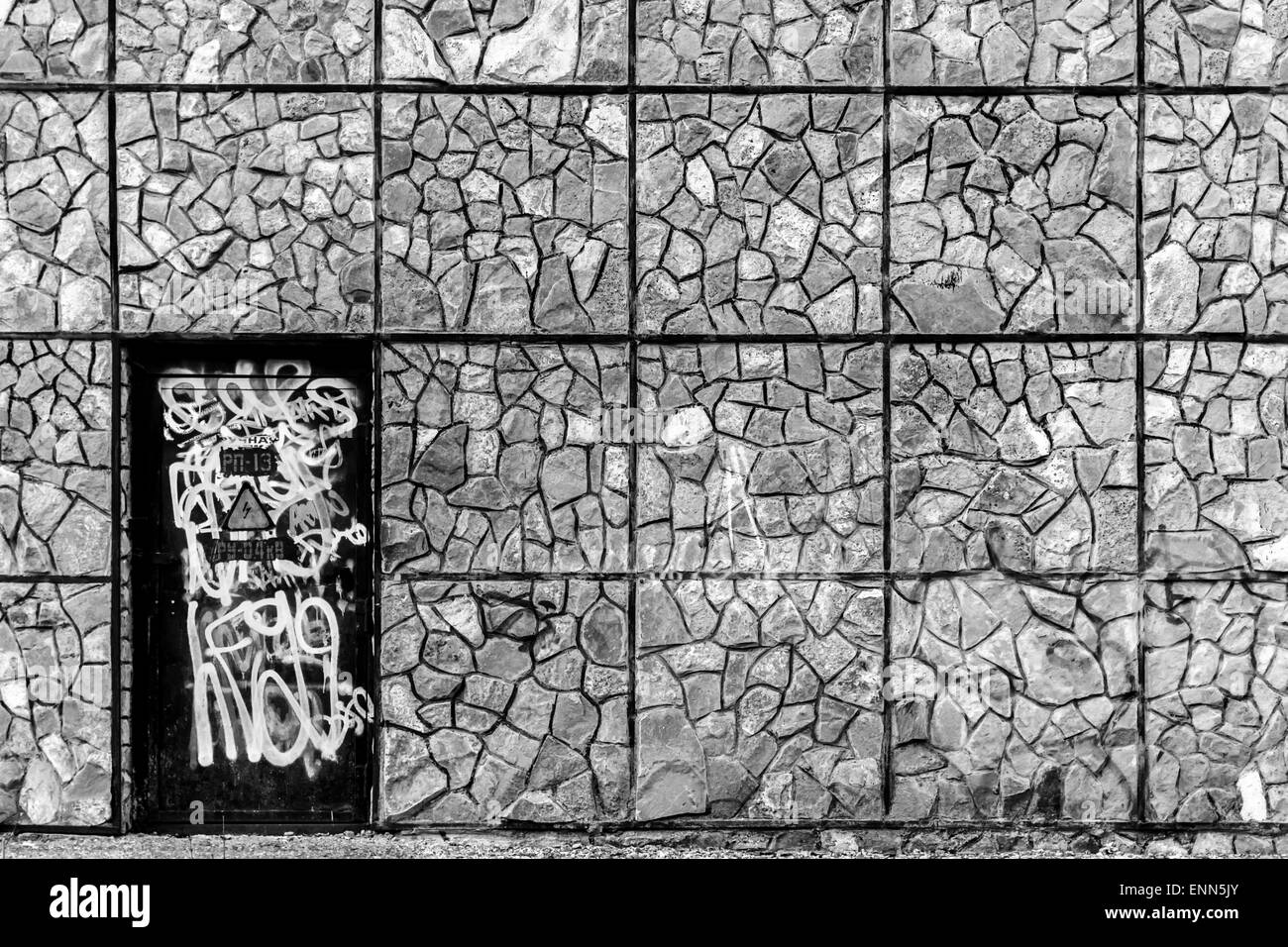 Verniciato a spruzzo porta nero circondato da un forte muro di mattoni in bianco e nero Foto Stock