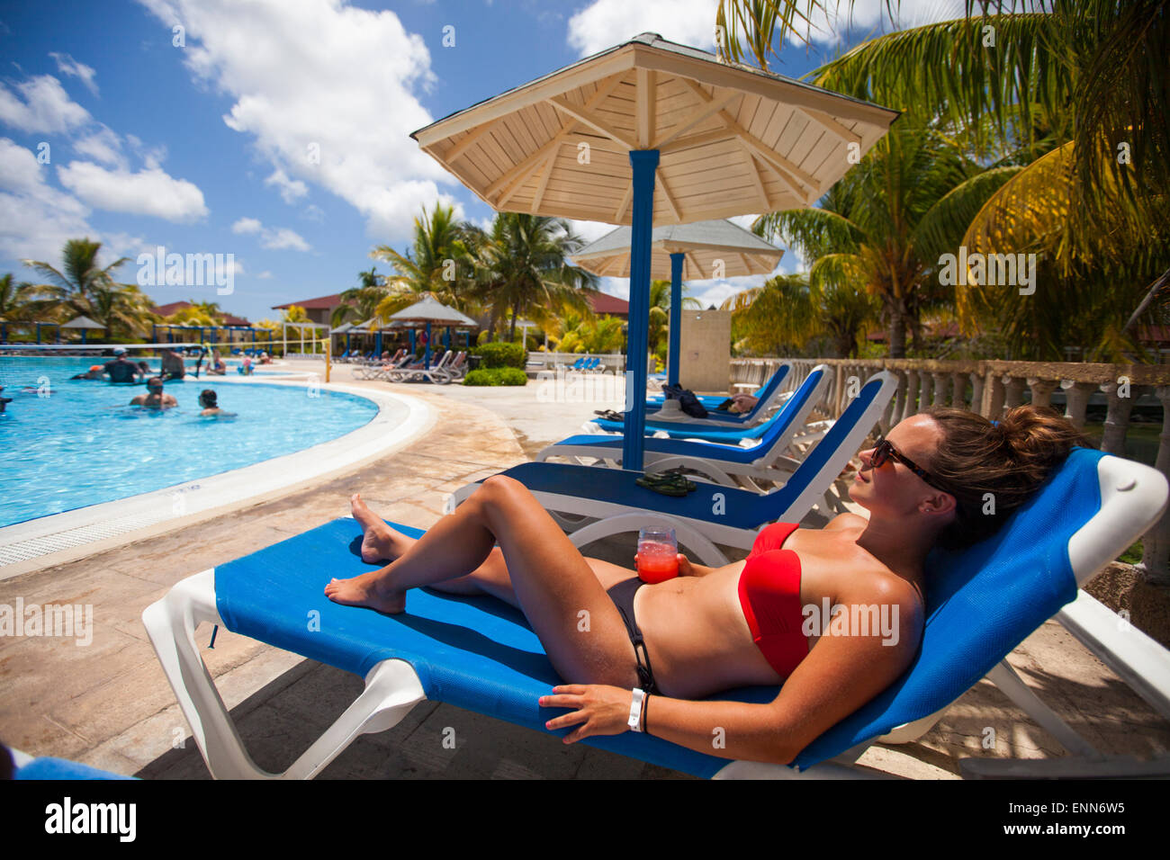 Una giovane donna che indossa un bikini rilassa accanto ad una piscina mentre è in vacanza in Cayo Coco, Cuba. Foto Stock