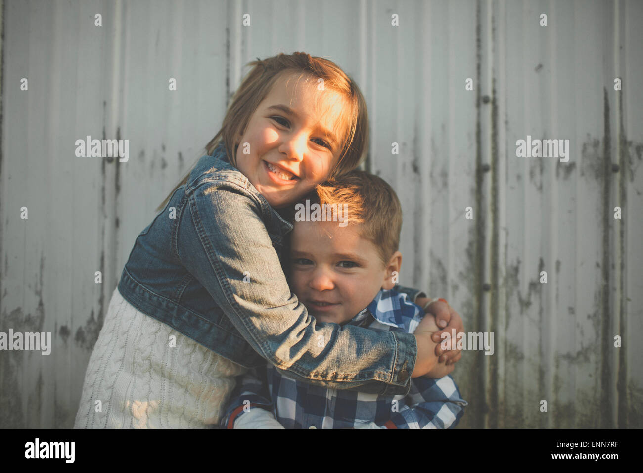 Una giovane ragazza dà il suo fratello più giovane di un abbraccio. Foto Stock