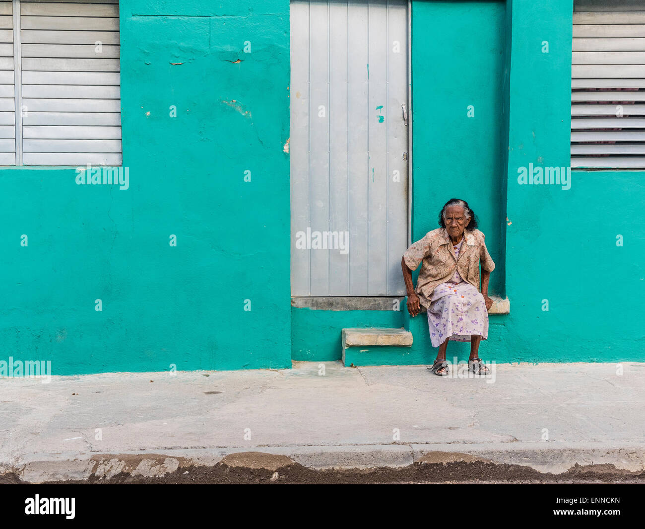 Senior afro-cubane nella porta di aqua edificio cercando infelice in Santiago de Cuba. Foto Stock