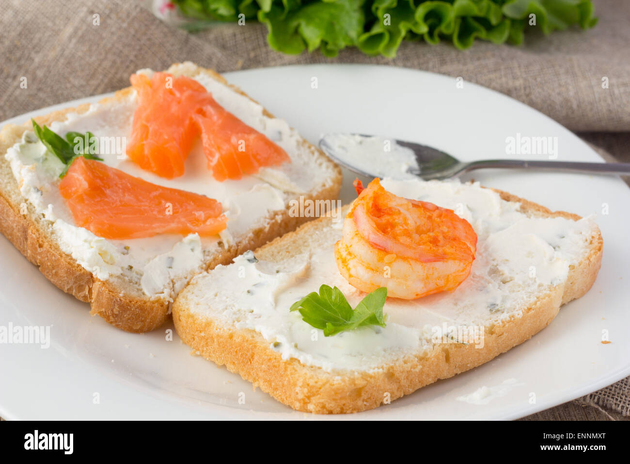 Pane di grano pane tostato con la crema di formaggio, salmone affumicato e gamberetti di messa a fuoco selettiva in orizzontale Foto Stock