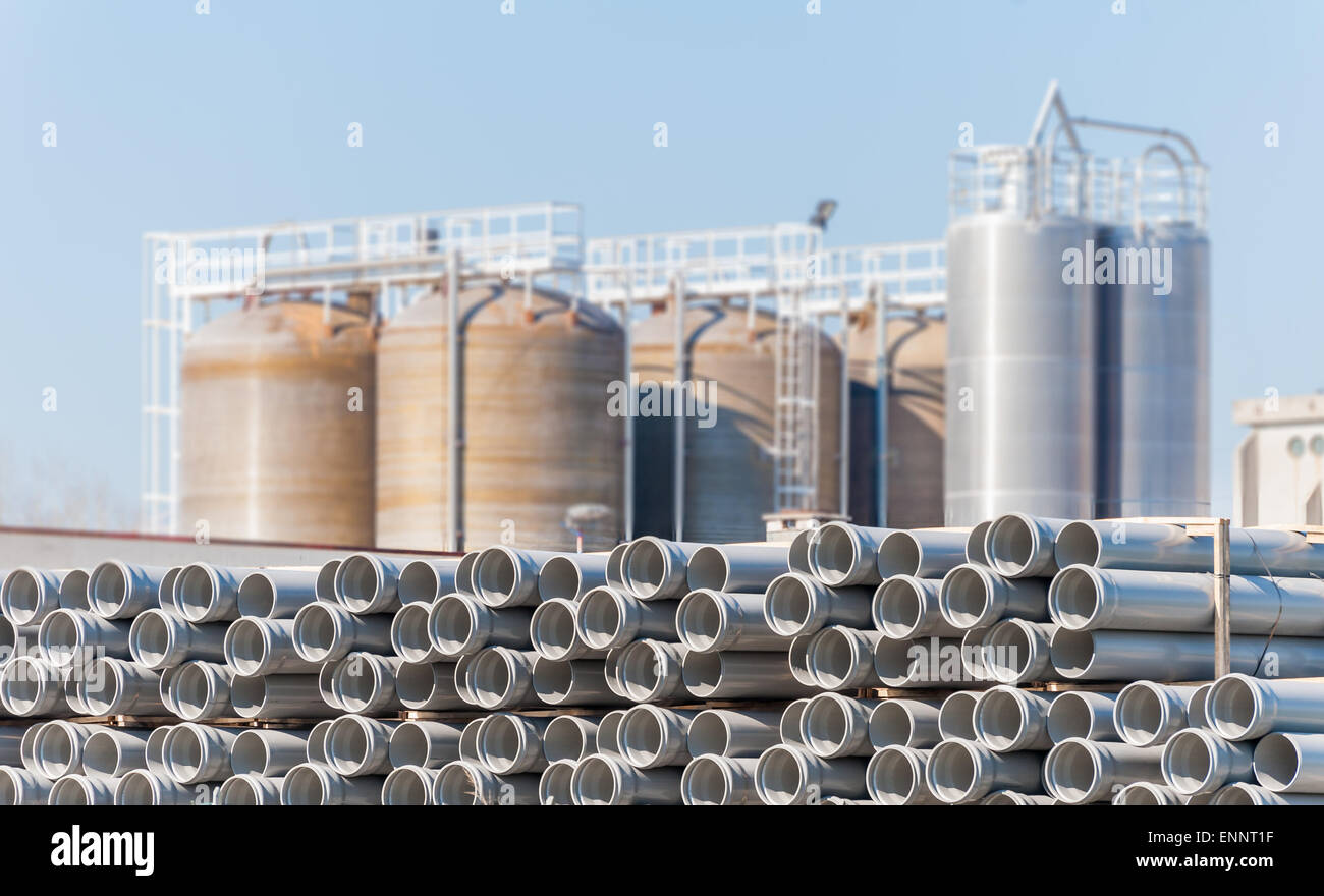 Tubi di plastica per condotte, con lo sfondo di impianto chimico silos. Foto Stock
