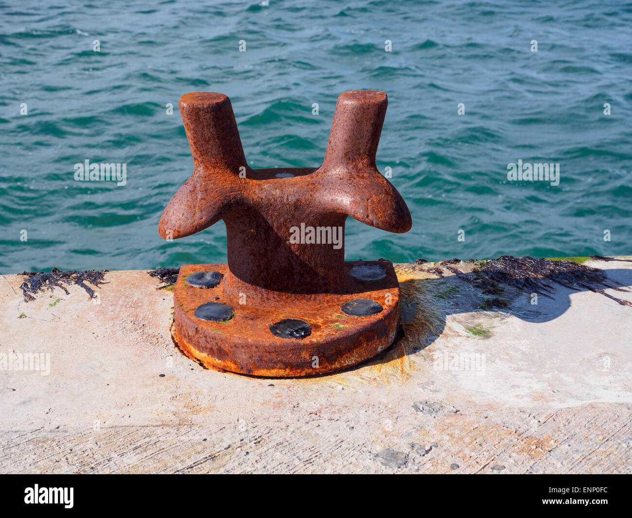 Un ferro arrugginito bollard per ormeggio navi, su un molo in Scozia. Foto Stock