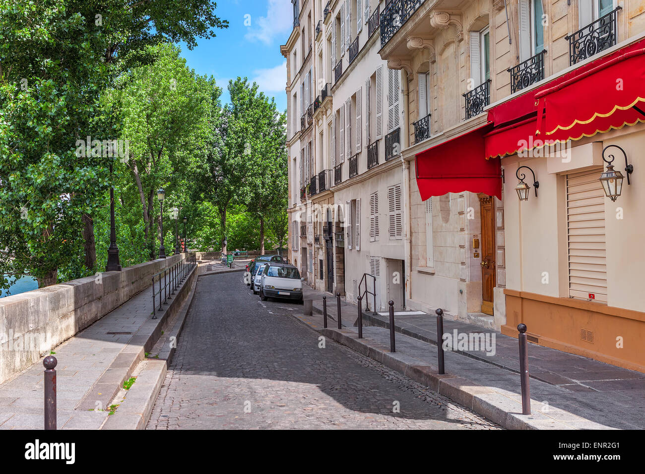 Stretta strada di ciottoli tra alberi verdi e tipico edificio parigino a Parigi, Francia. Foto Stock