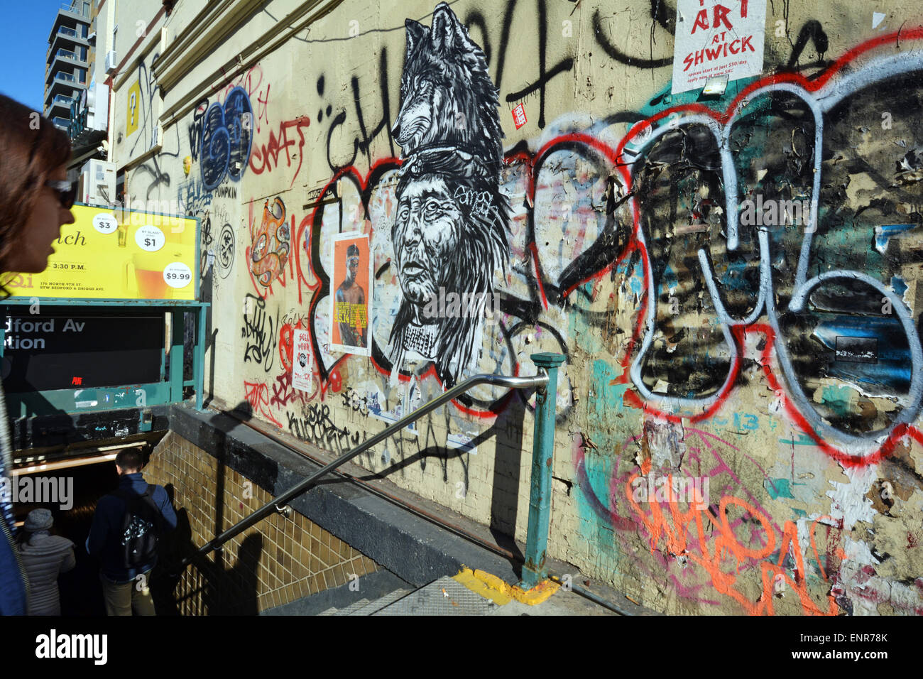 I " commuters " immettere il L la linea metropolitana Bedford Avenue a Williamsburg, Brooklyn come essi passano un graffiti riempito parete. Foto Stock