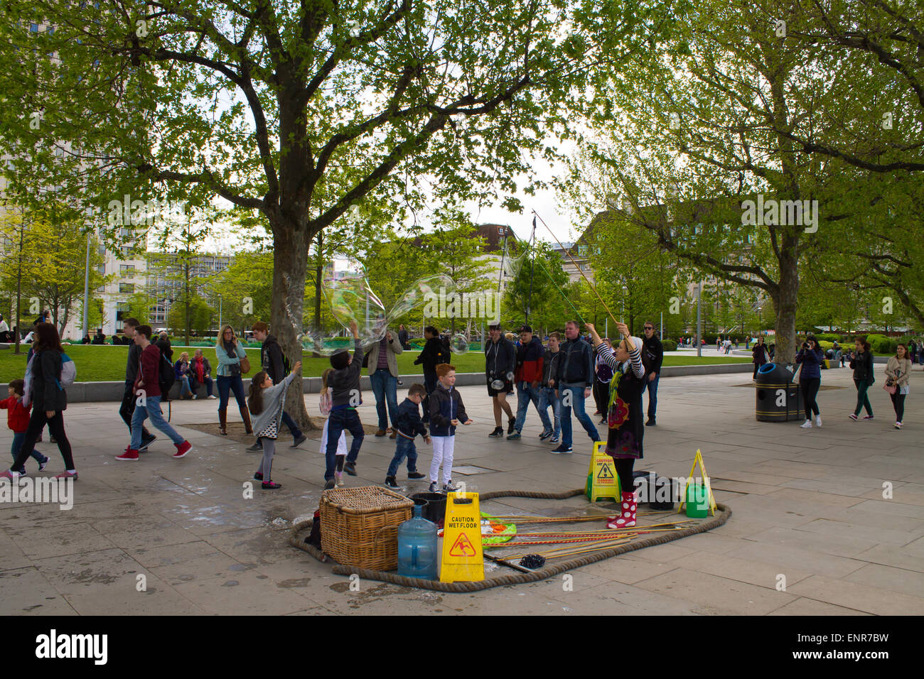 I turisti in Embankment Gardens, Londra, Regno Unito. Bolla di sapone artista intrattenere i bambini. Foto Stock