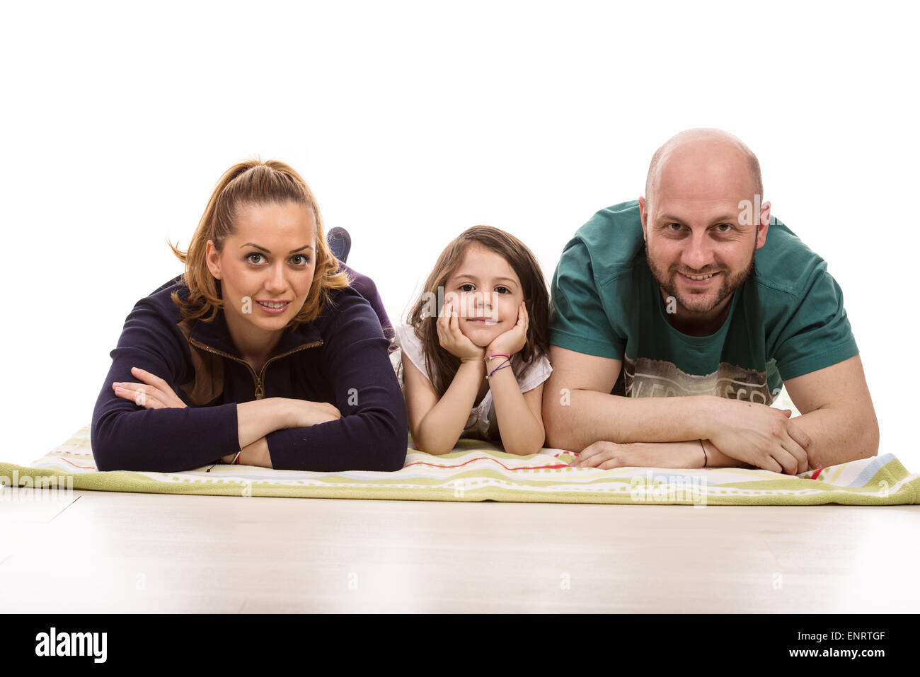 Felice di tre membri della famiglia la posa su una coperta in una fila contro uno sfondo bianco Foto Stock
