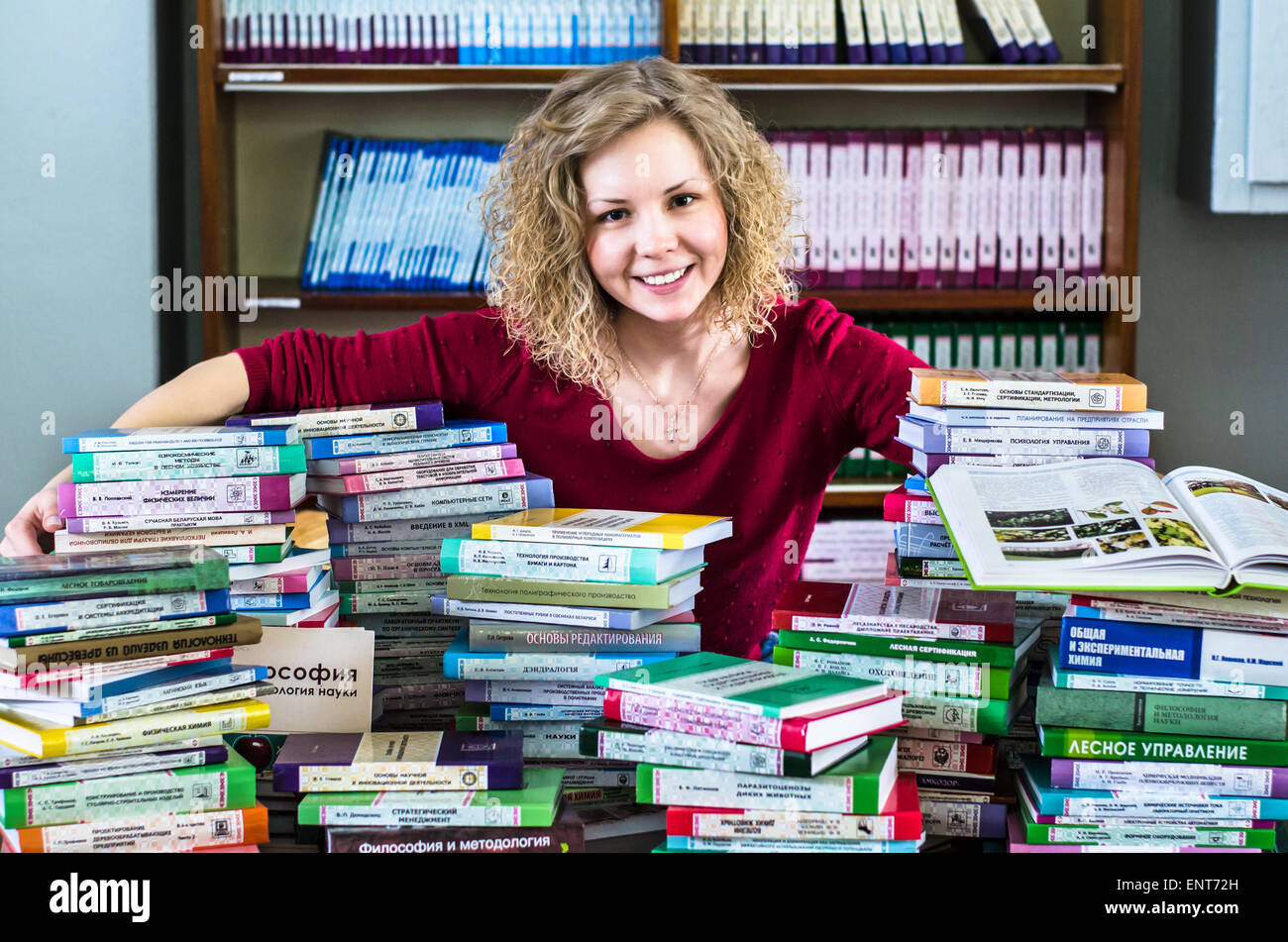 Una ragazza sono trasportano informazioni sulle pile di libri e chiedendo circa i buoni contrassegni Foto Stock