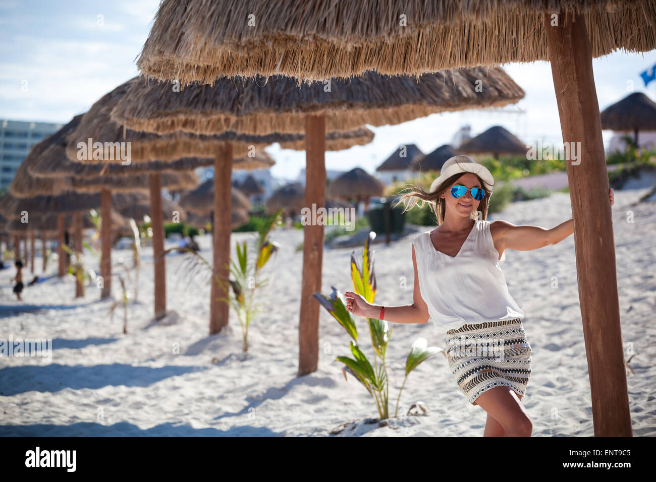 Bella donna abbronzata in posa di ombrellone in spiaggia palapa, godendo le vacanze estive Foto Stock