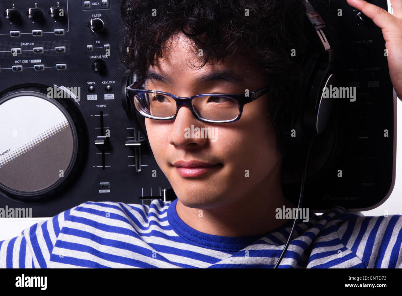 Asian giovane uomo che guarda lontano azienda digital girare a tavola di indossare le cuffie Foto Stock