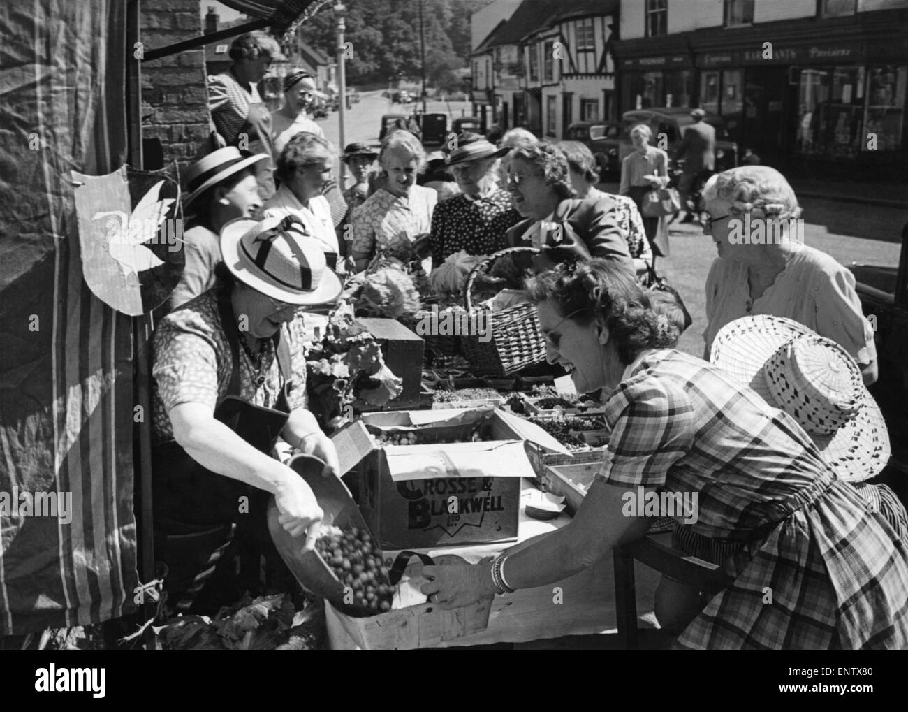 Stanchi di vedere sviluppati internamente la frutta e la verdura che vanno sprecate, volontario dei membri della Chalfont, St. Giles le donne dell'Istituto sono in esecuzione questo stallo, aperto a tutti gli angoli. Le donne con eccedenza di produzione di portarlo alla stalla, dove le casalinghe senza giardini comprarlo ardentemente. Istituto club dei membri insieme per acquistare macchine di inscatolamento di mantenere alcuni dei frutti per l'inverno. Luglio 1949 Foto Stock