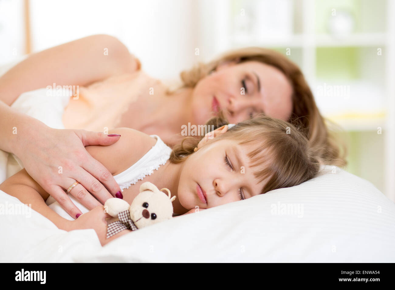 La ragazza del bambino con la madre preparare per napping sul letto in camera da letto Foto Stock