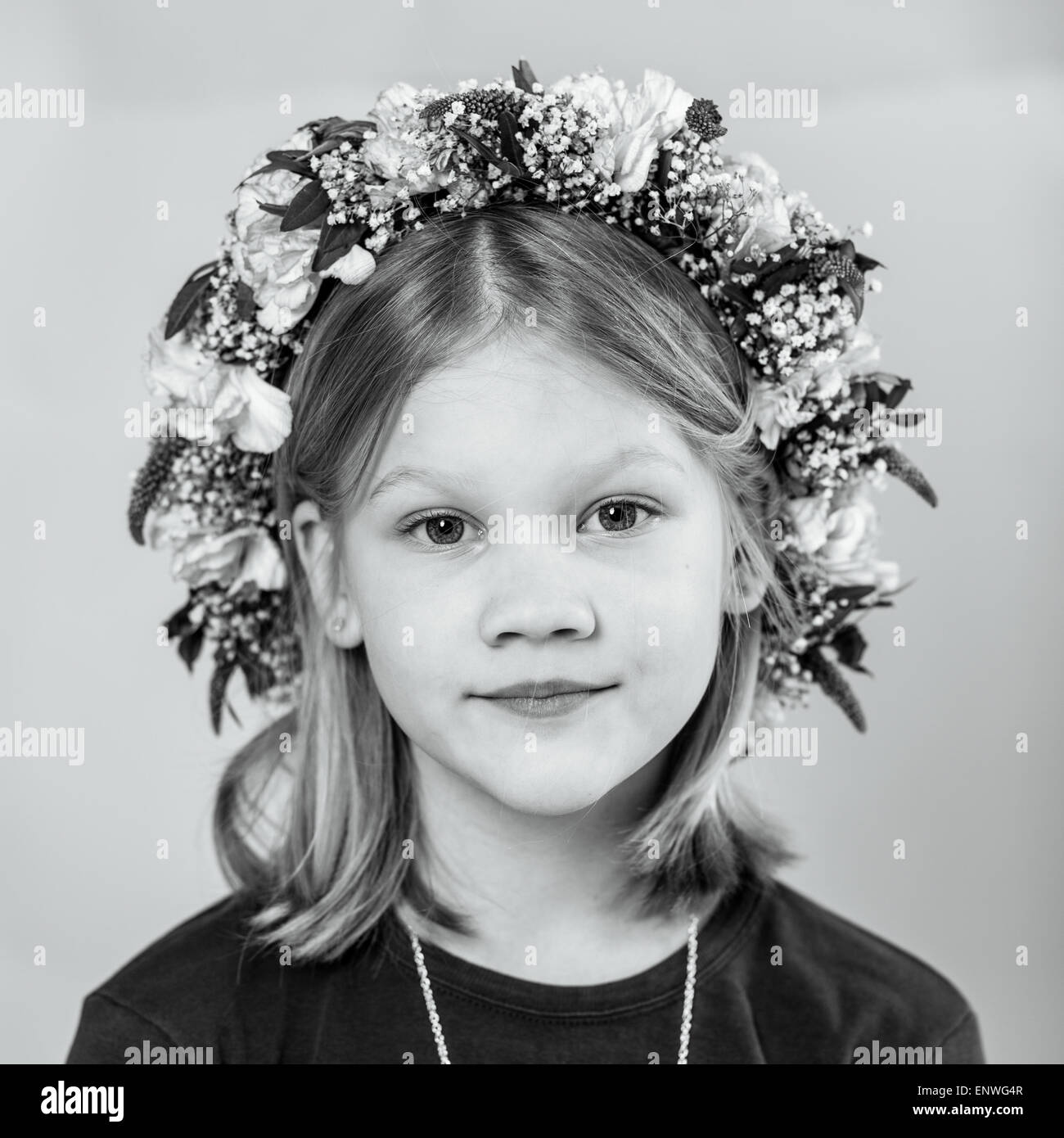 Ritratto di una incantevole piccola ragazza con una ghirlanda di fiori su i suoi capelli, in bianco e nero Foto Stock
