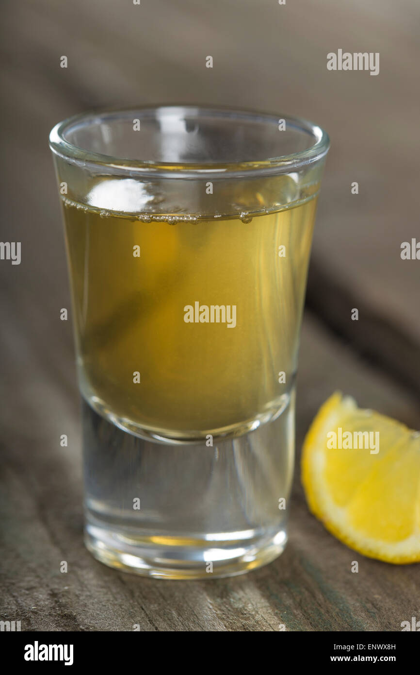 Tequila shot con limone sul legno scuro dello sfondo. DOF poco profondo Foto Stock