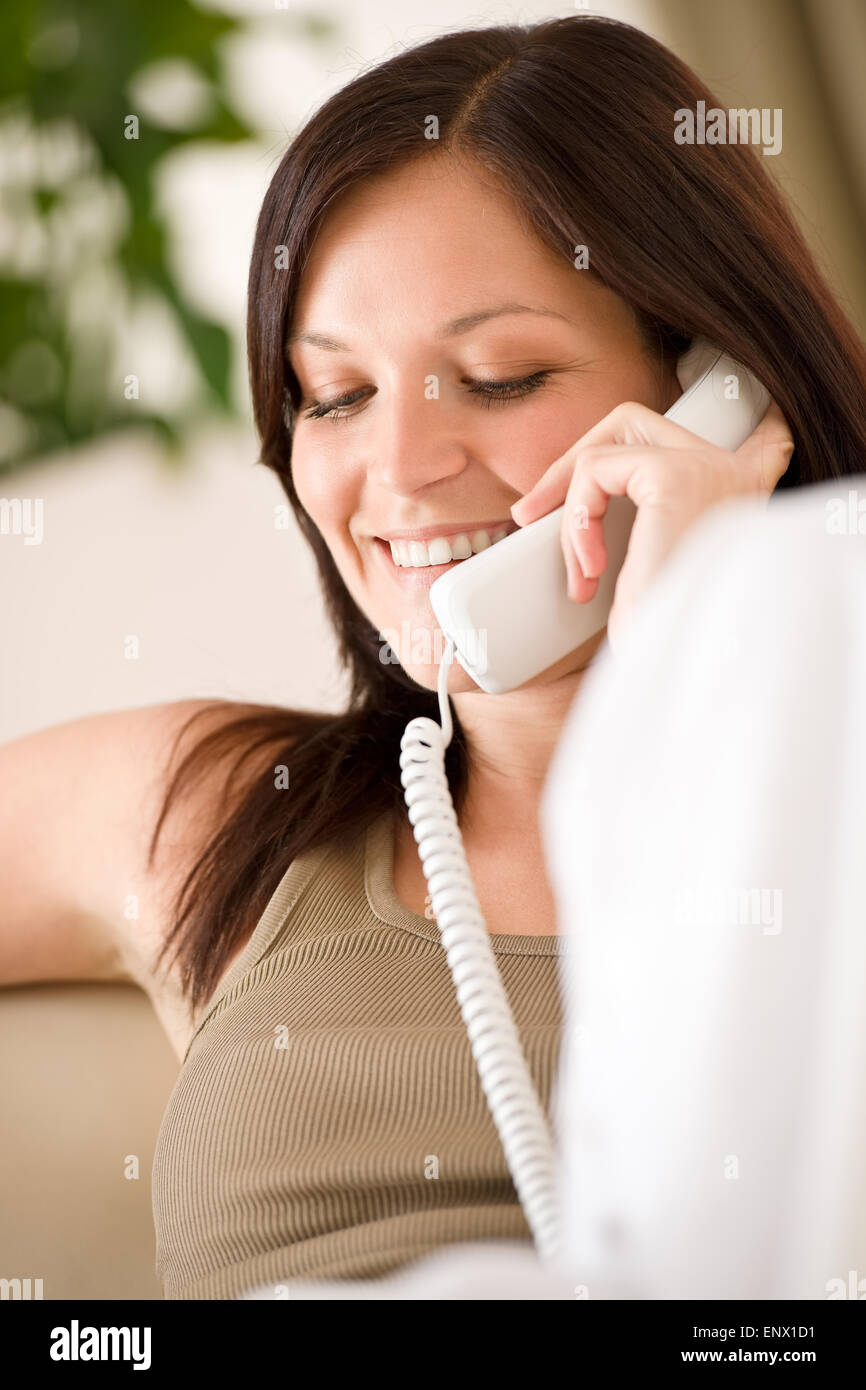 Sul telefono home - donna sorridente sul divano chiamando Foto Stock