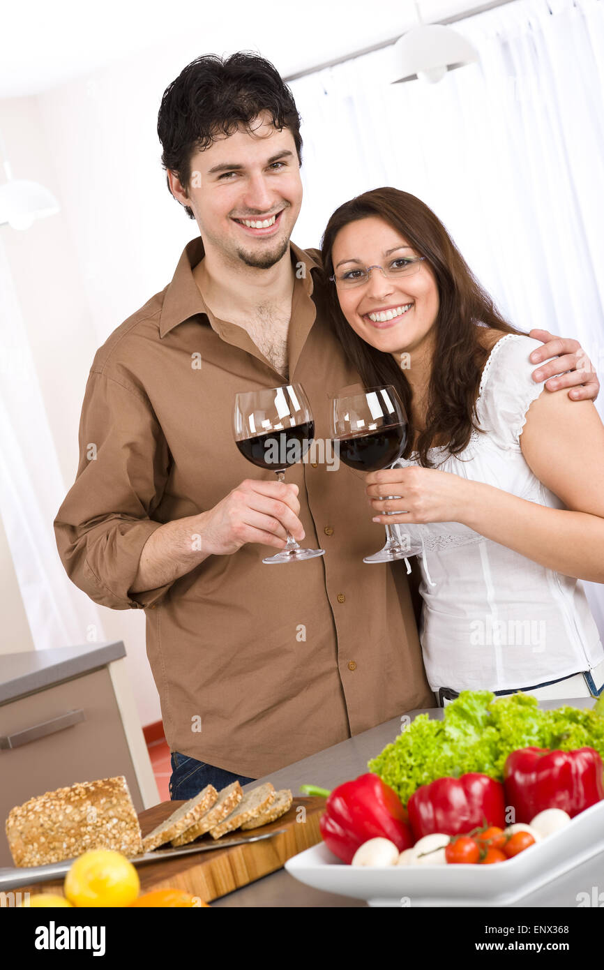 Coppia felice bere il vino rosso in cucina moderna Foto Stock