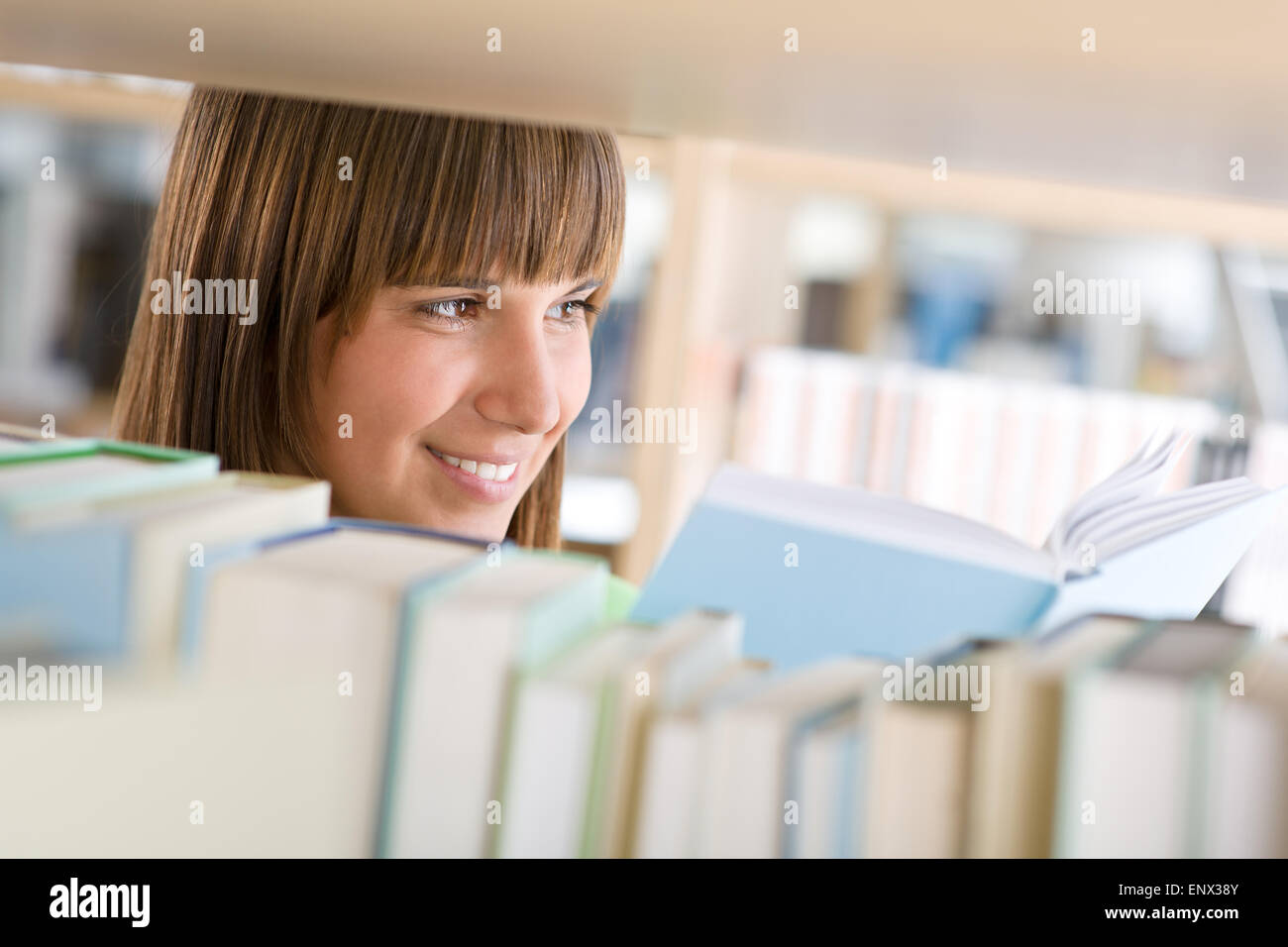 Studente in biblioteca - donna felice studio dal libro Foto Stock
