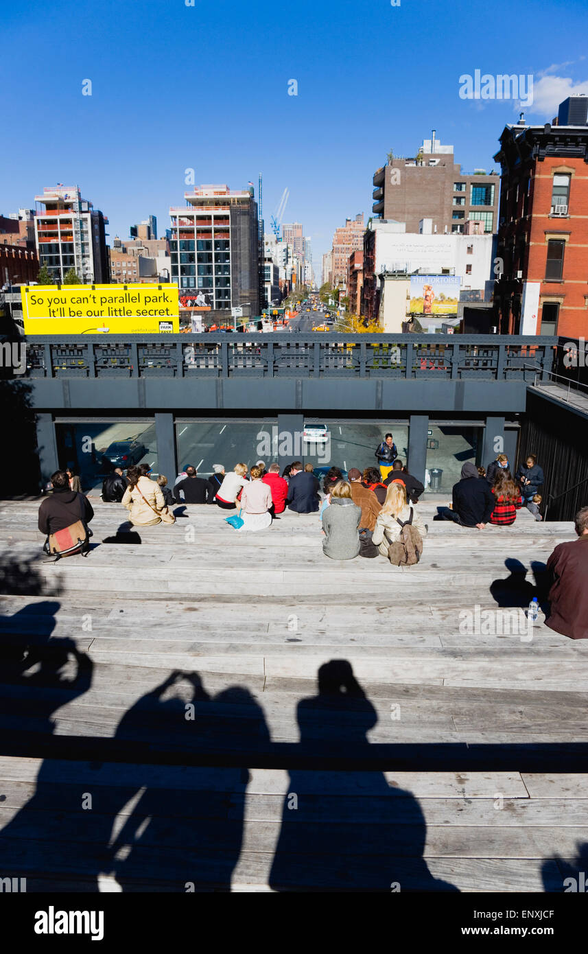 Stati Uniti d'America, New York Manhattan, persone sedute sul decimo Avenue Square piattaforma di osservazione sulla linea alta un parco lineare su una elevata sezione in disuso della ferrovia guardando il traffico sulla strada sottostante. Foto Stock