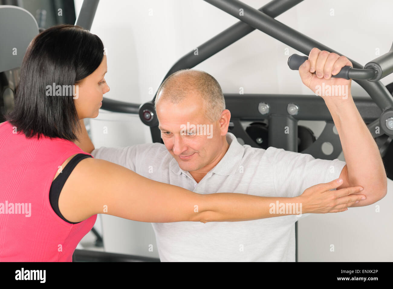 Centro fitness trainer assiste l uomo esercizio indietro Foto Stock