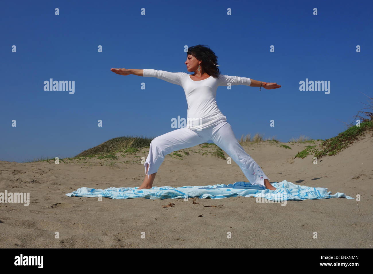 Donna matura la pratica dello Yoga pone sulla spiaggia sabbiosa Foto Stock