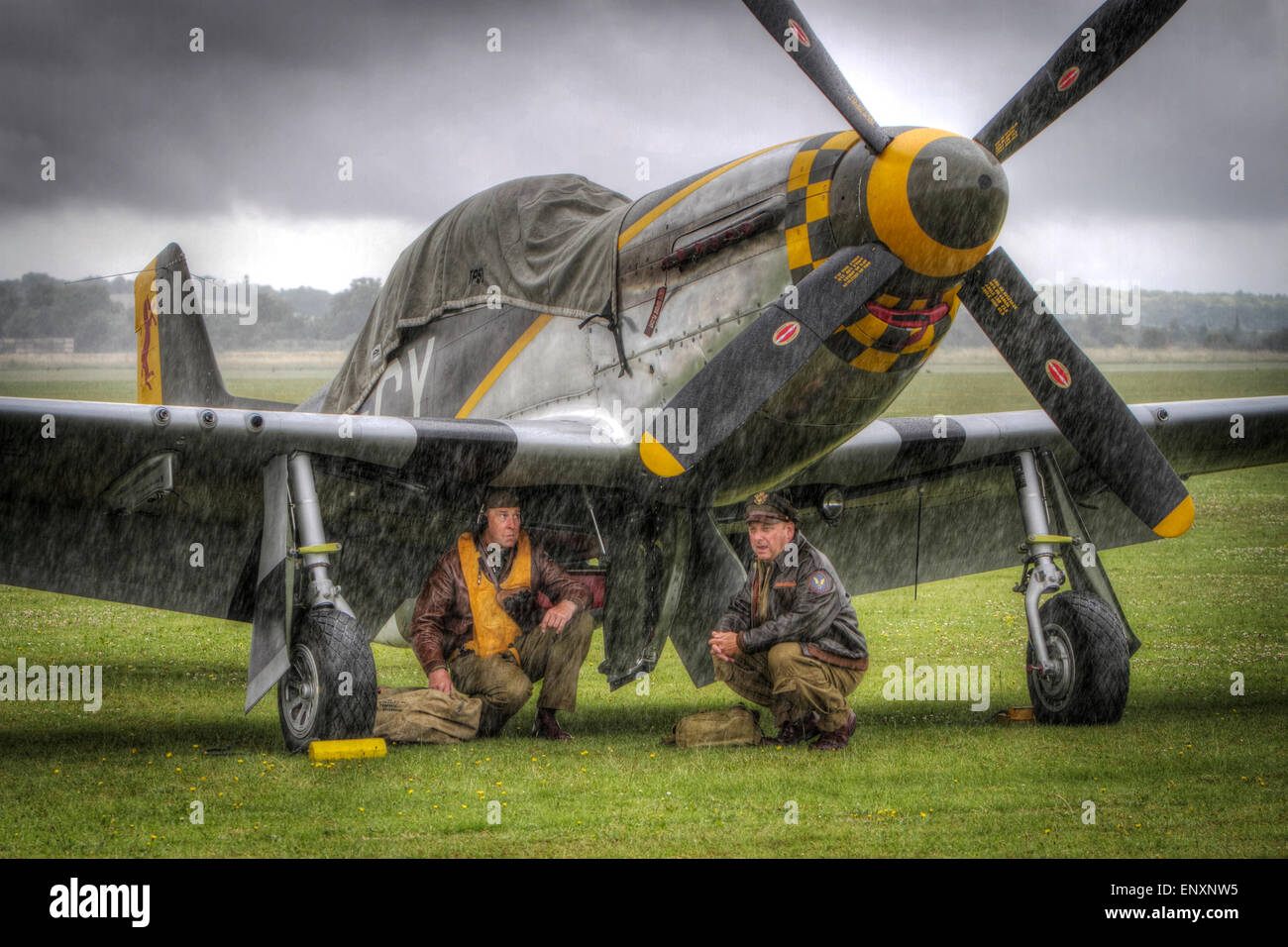 Guerra Mondiale 2 re-enactors rifugio al di sotto di un P Mustang durante il Flying Legends show a RAF Duxford Foto Stock