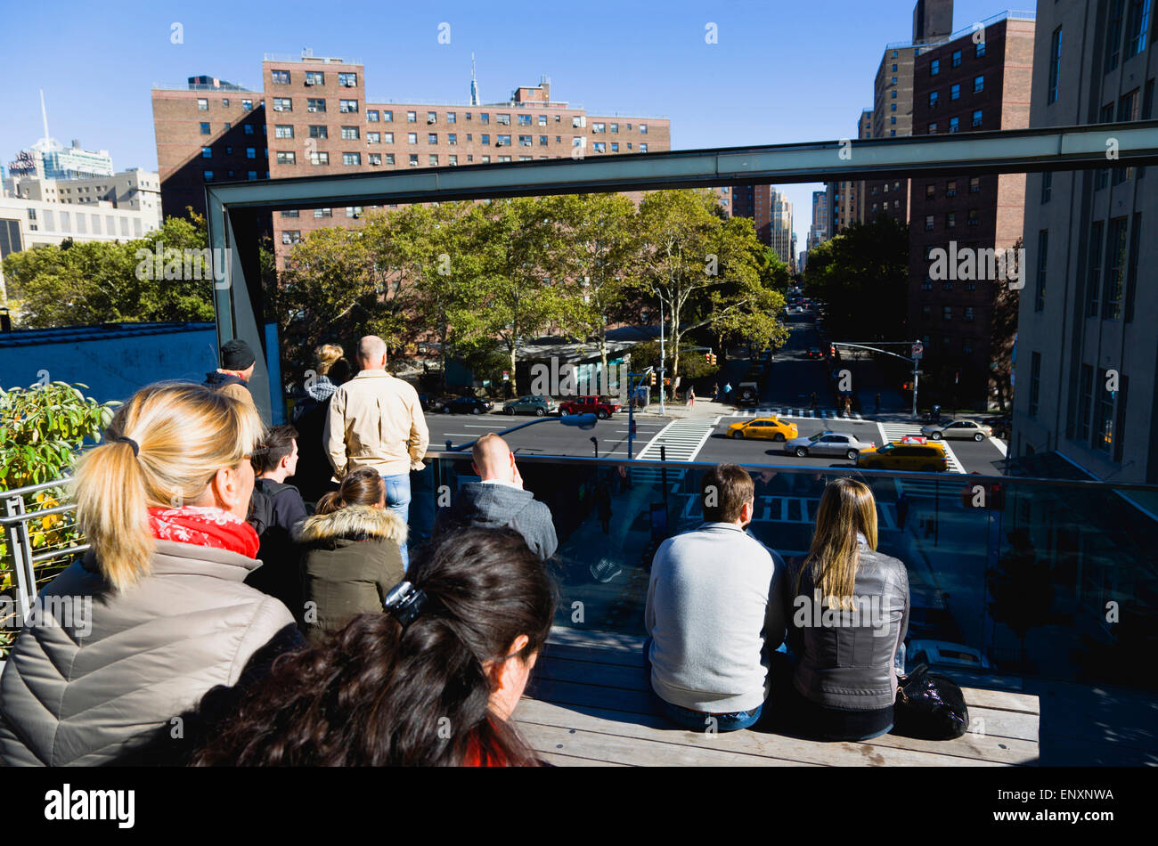 Stati Uniti d'America, New York Manhattan, persone sedute al 26th Street sperone di visualizzazione sulla linea alta parco lineare su un disuso ferrovia sopraelevata a guardare il traffico sulla strada sottostante. Foto Stock