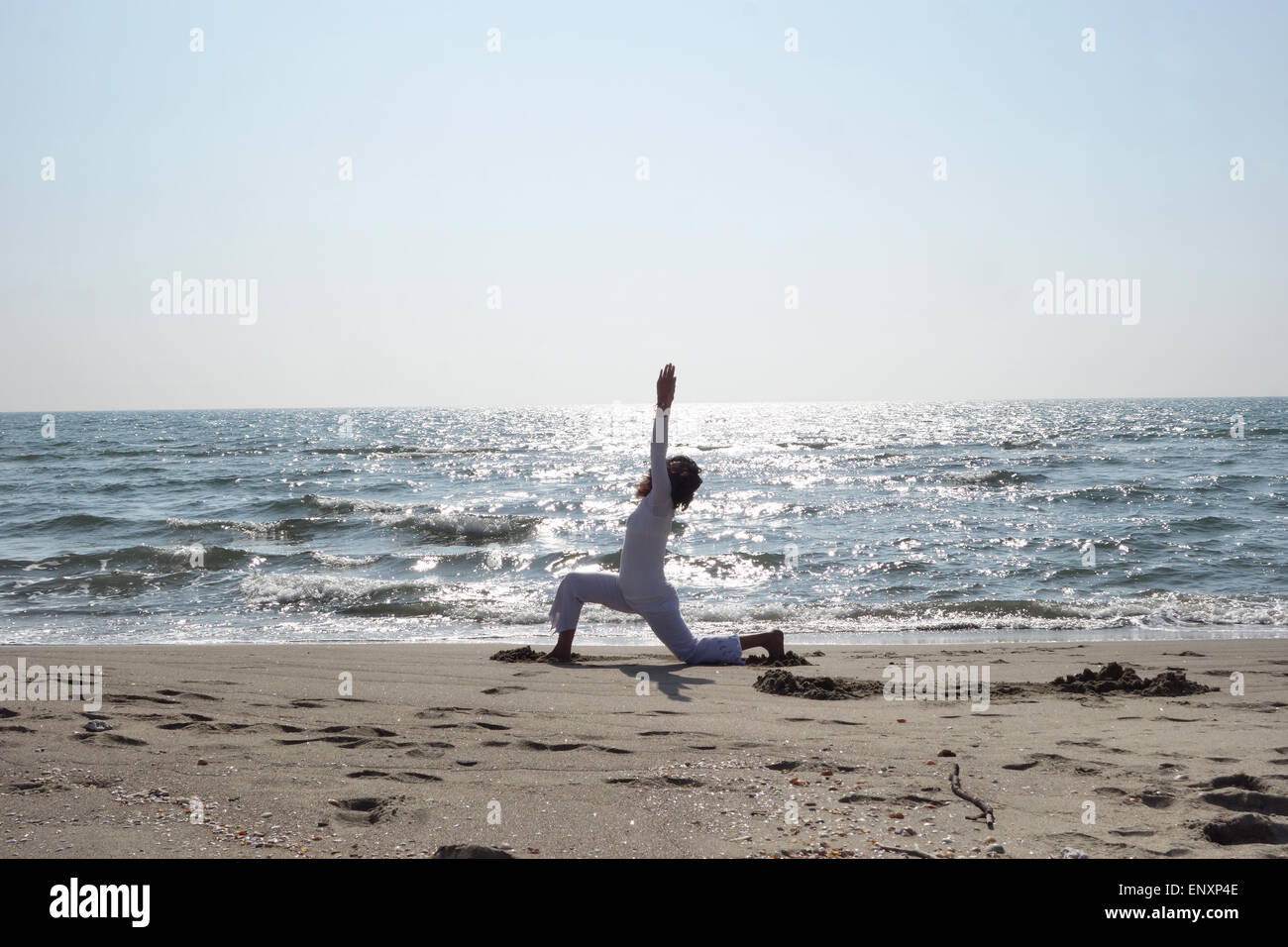 Donna matura la pratica dello Yoga pone sulla spiaggia sabbiosa Foto Stock