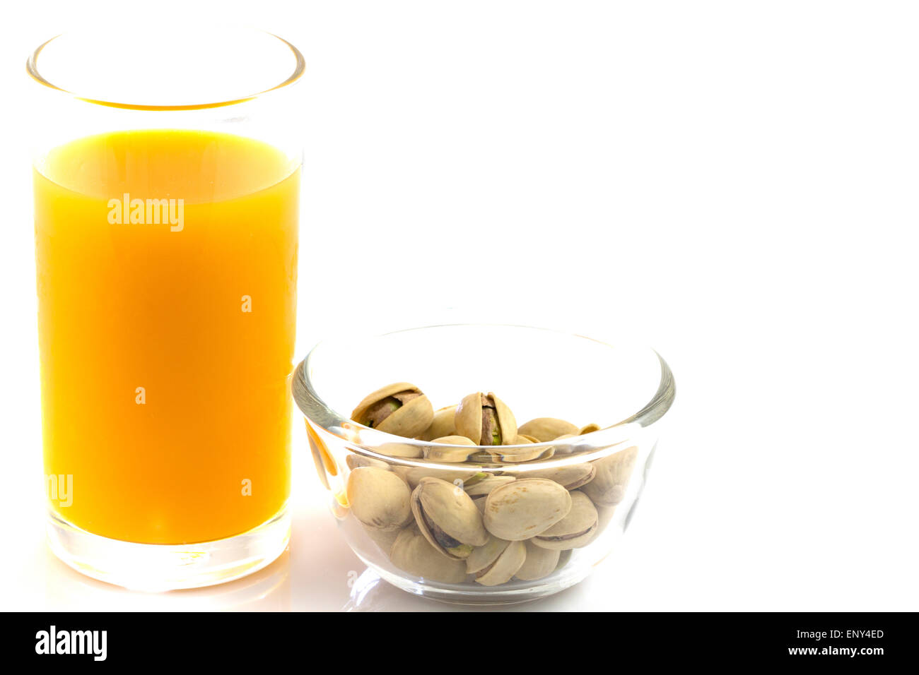 I pistacchi in una lastra di vetro e un bicchiere di succo di arancia isolato su bianco Foto Stock