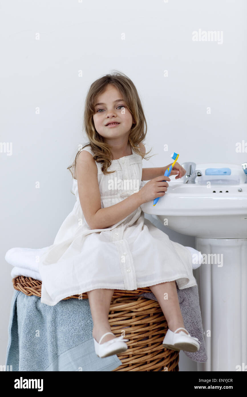 Poco ragazza seduta in bagno la pulizia i suoi denti Foto Stock