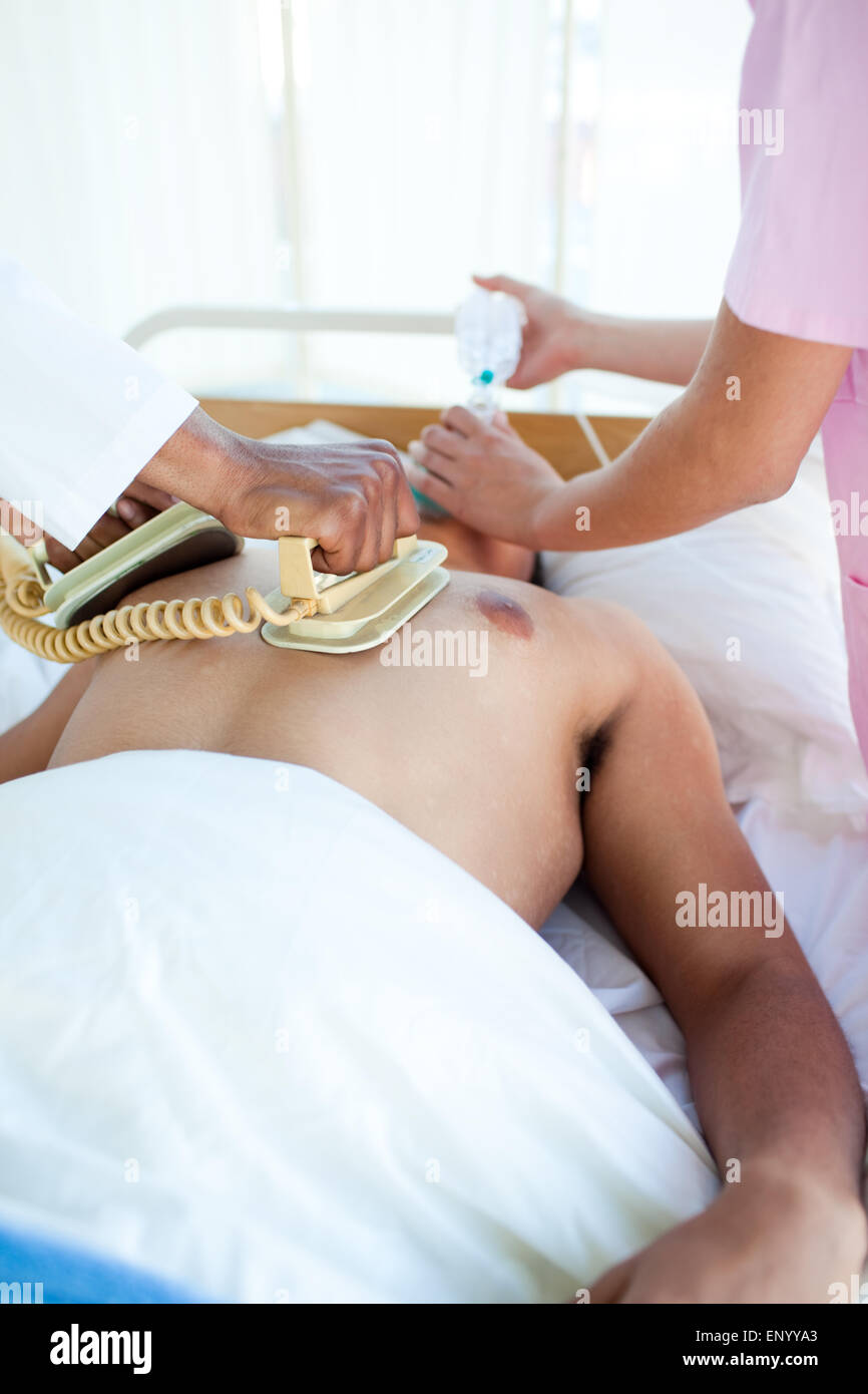 Un medico di eseguire una rianimazione cardiopolmonare con un defibrillatore su un paziente Foto Stock